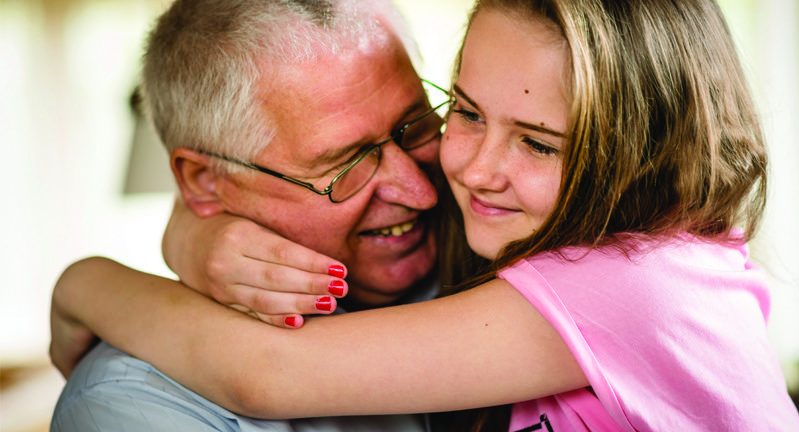 Young girl in pink top hugging smiling man