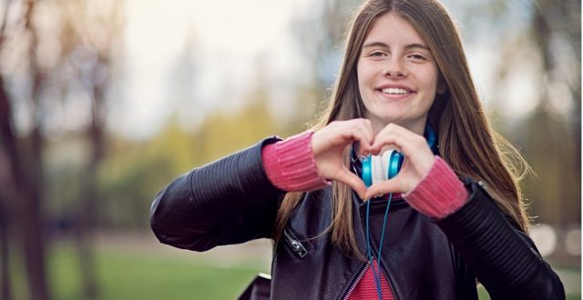 A teenage girl making a heart shape with her hands