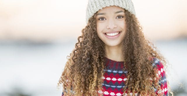 A portrait of a beautiful mixed race teenager enjoying her time outside during winter time. She wears warm clothing and a winter hat.